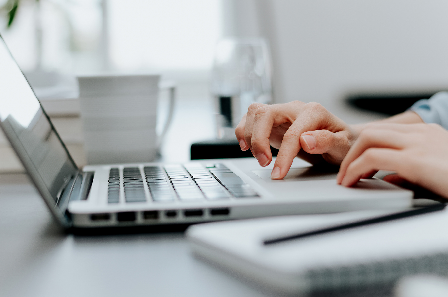 Close up image of woman's hand working on laptop in office.